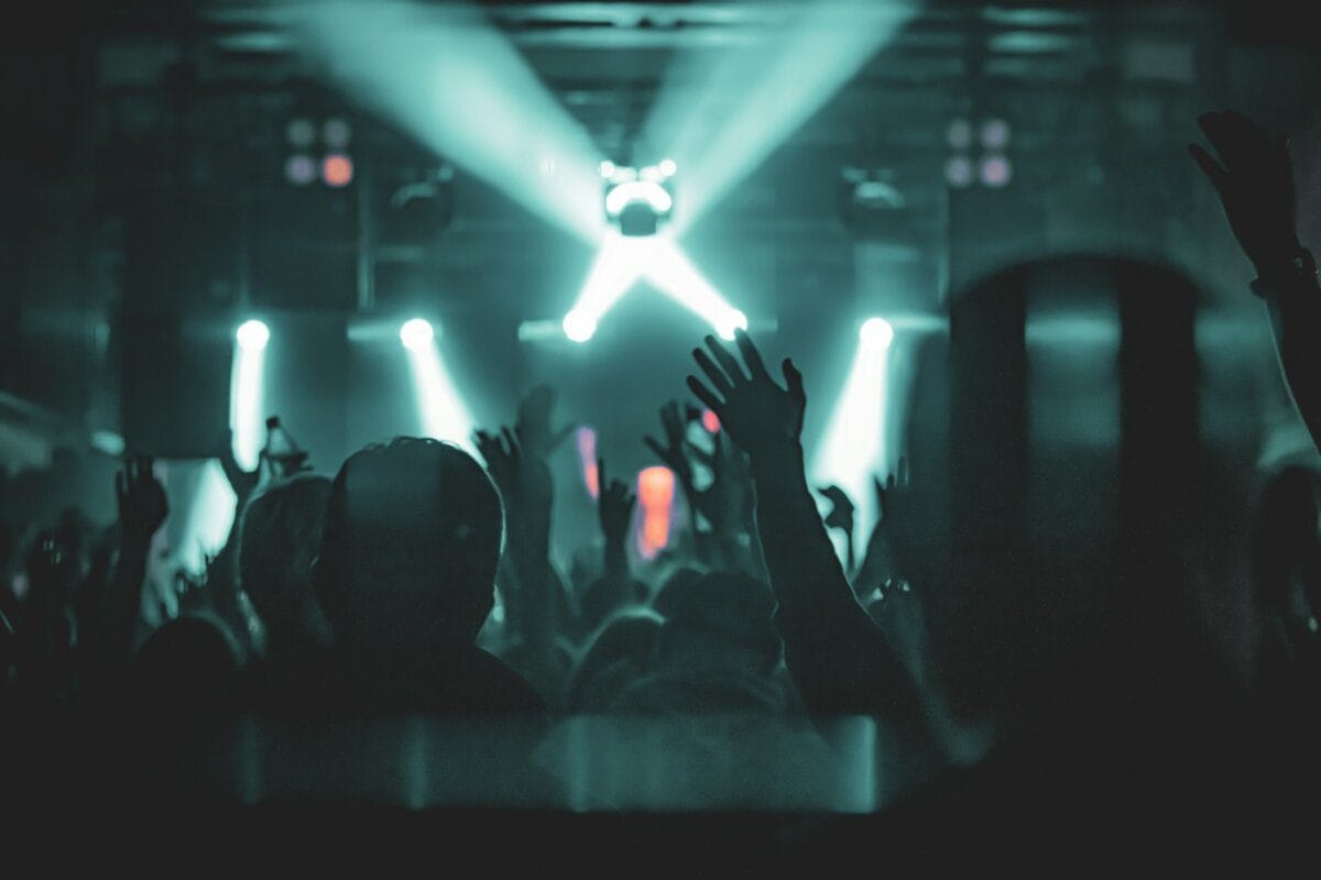 Crowd with hands raised at a concert with colorful stage lights