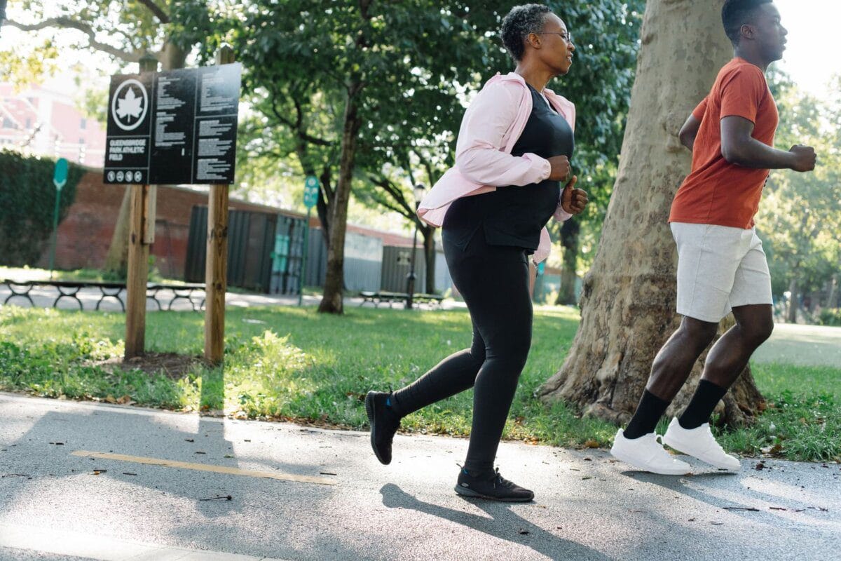 A young man and an elderly woman jogging together in a park
