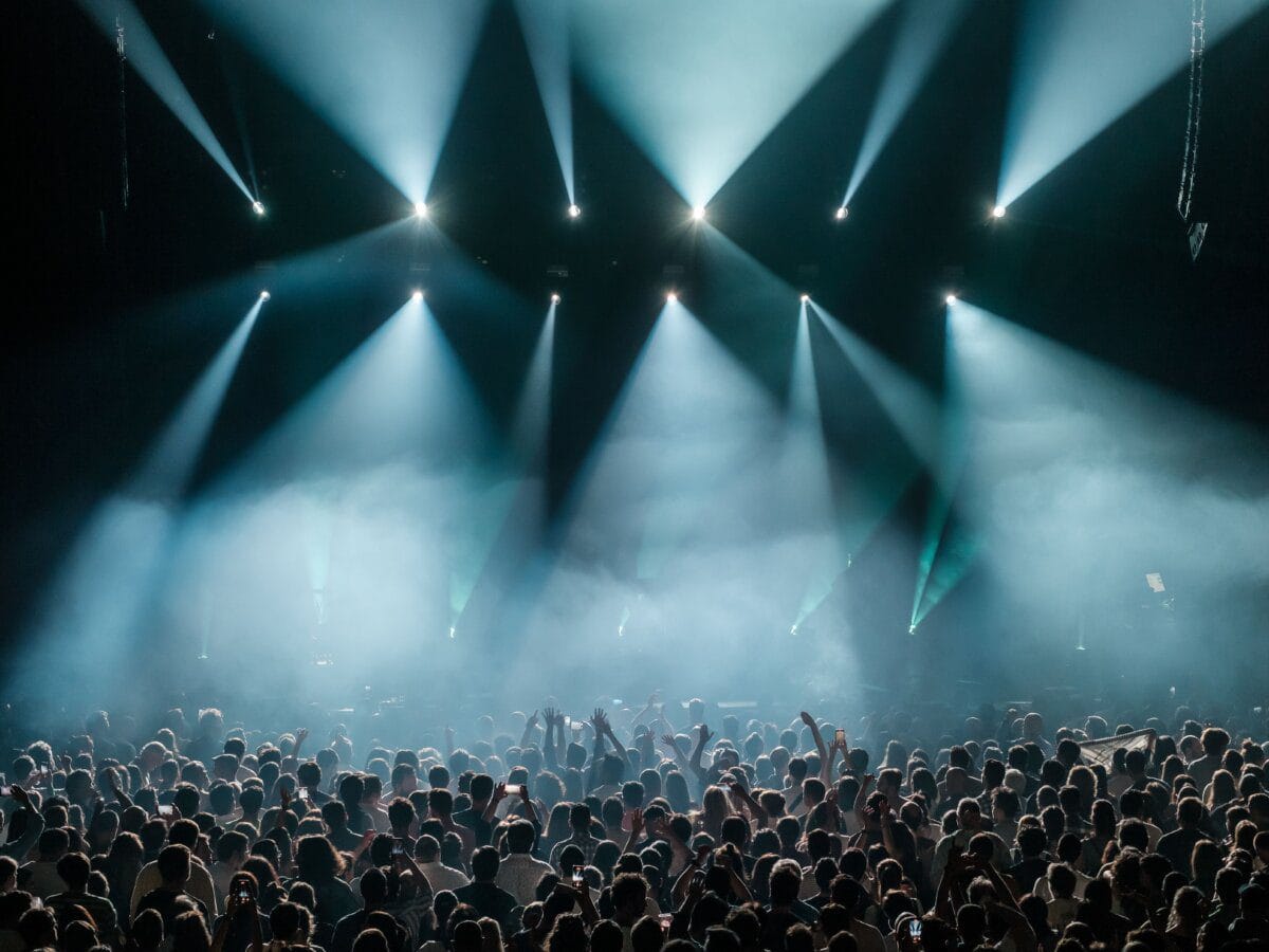 A large concert crowd under stage lighting
