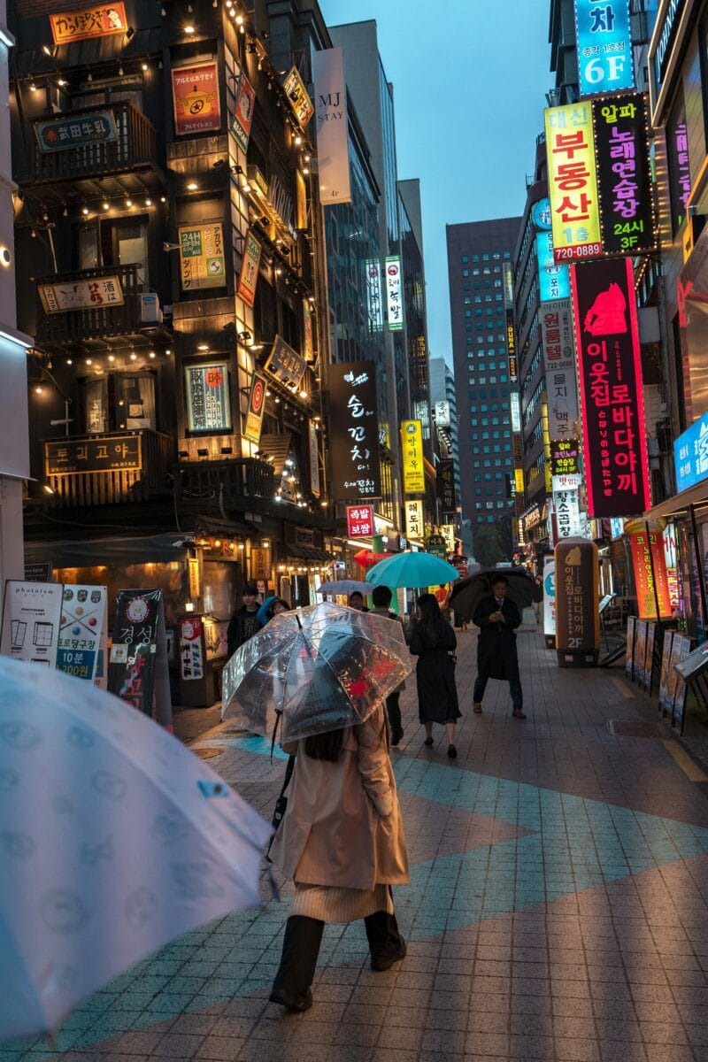 Pedestrians walking with umbrellas on a busy Seoul street